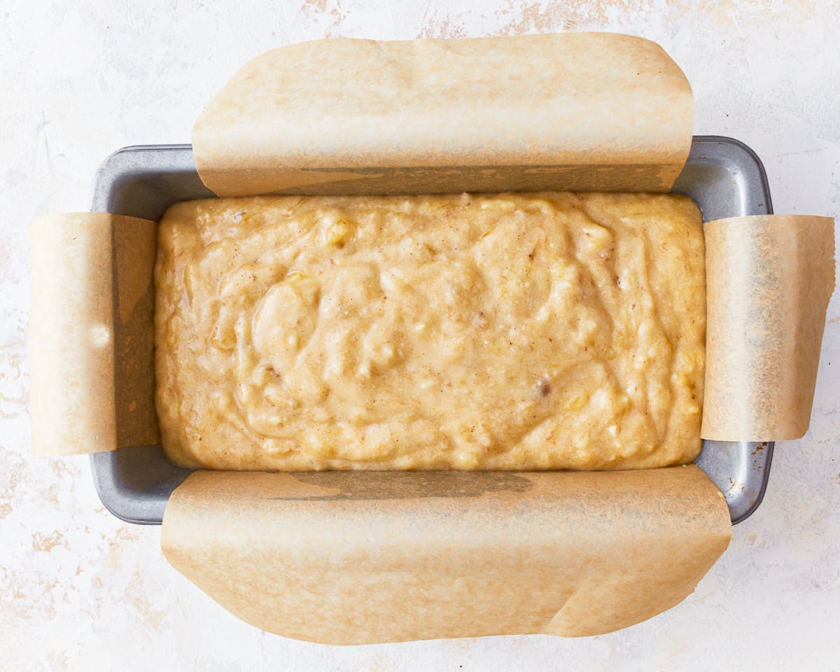 gluten-free banana bread batter in a lined loaf pan.