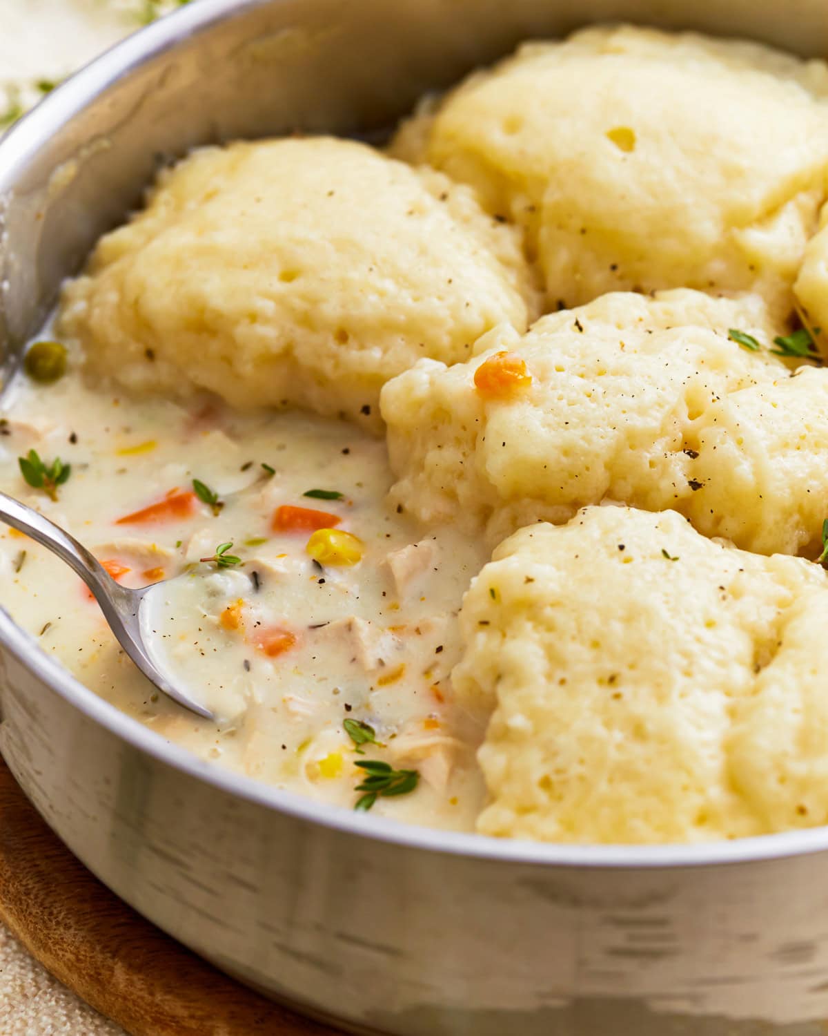 A spoon scooping gluten-free chicken and dumplings from the pan