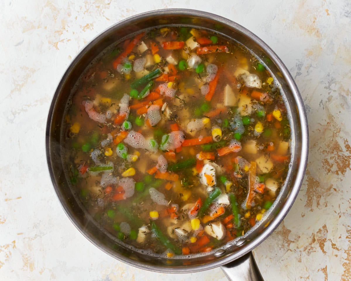 Frozen vegetables and seasonings in a pot for gluten-free chicken and dumplings