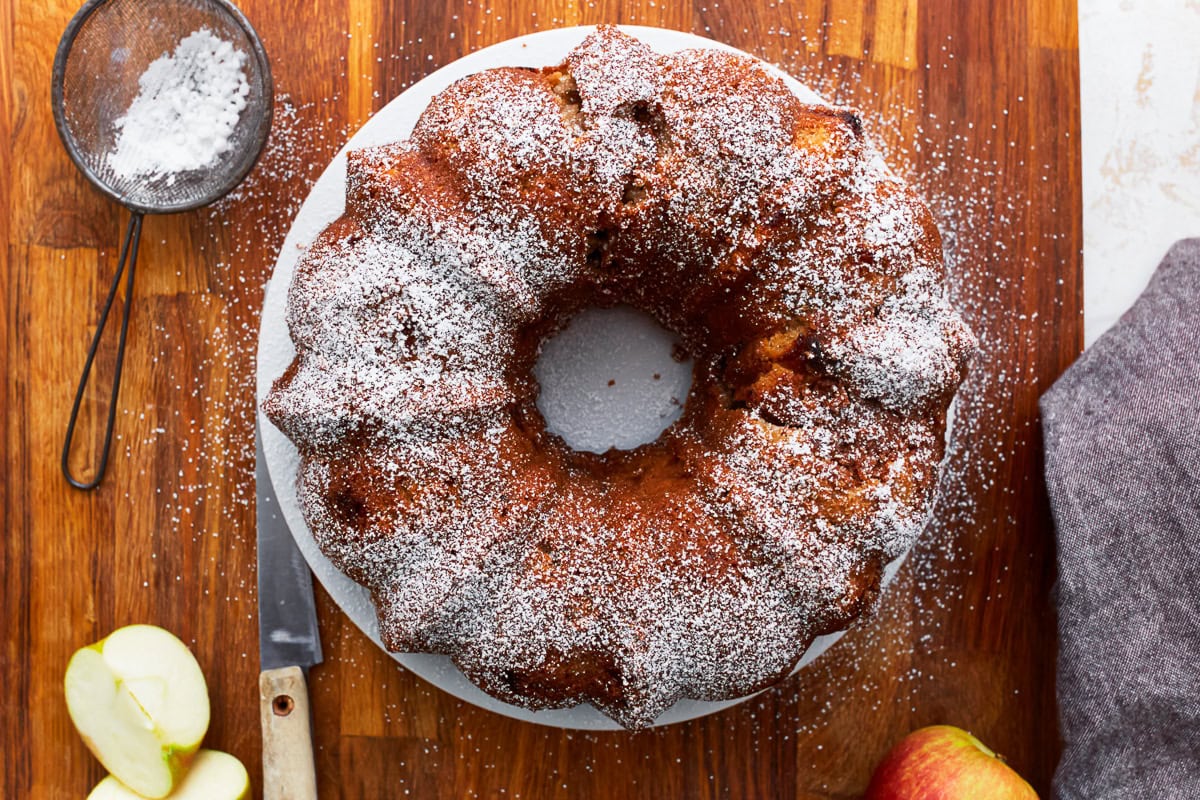 Overhead view of a gluten-free apple cake cut sprinkled with powdered sugar.