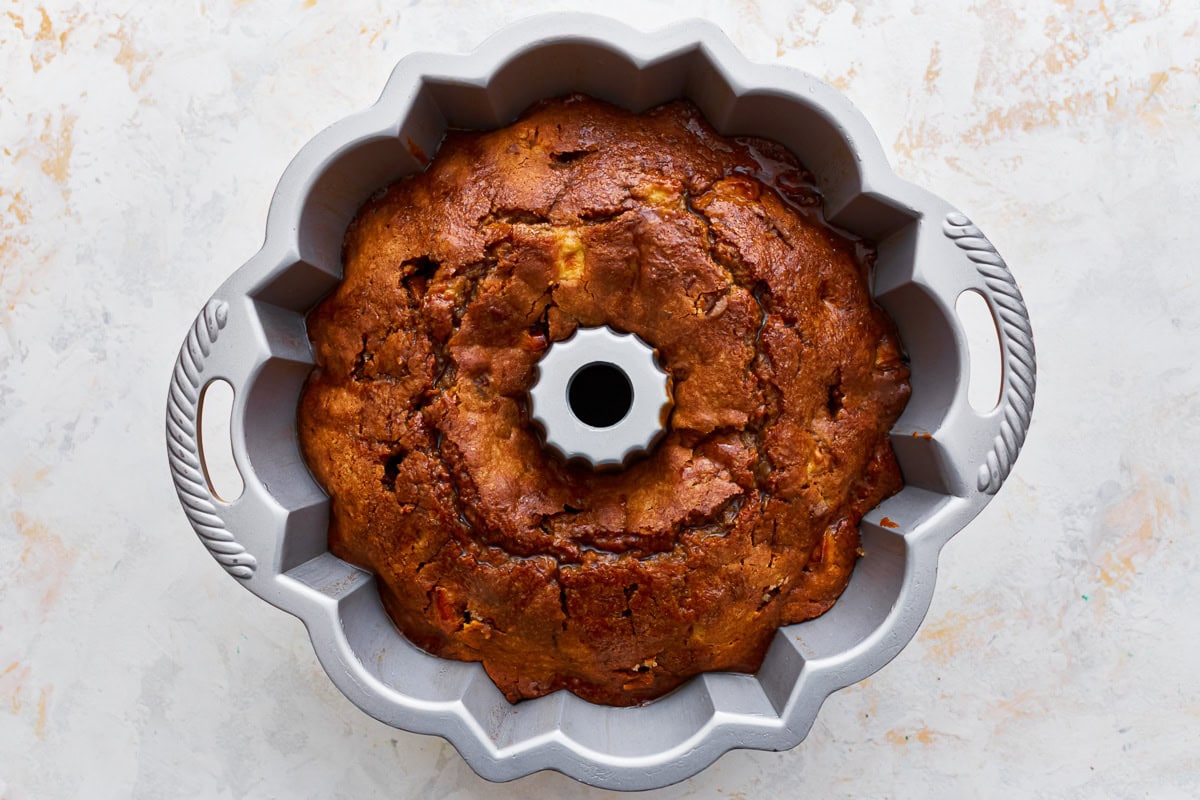 Gluten-free apple cake in a bundt pan with brown sugar glaze poured on top.