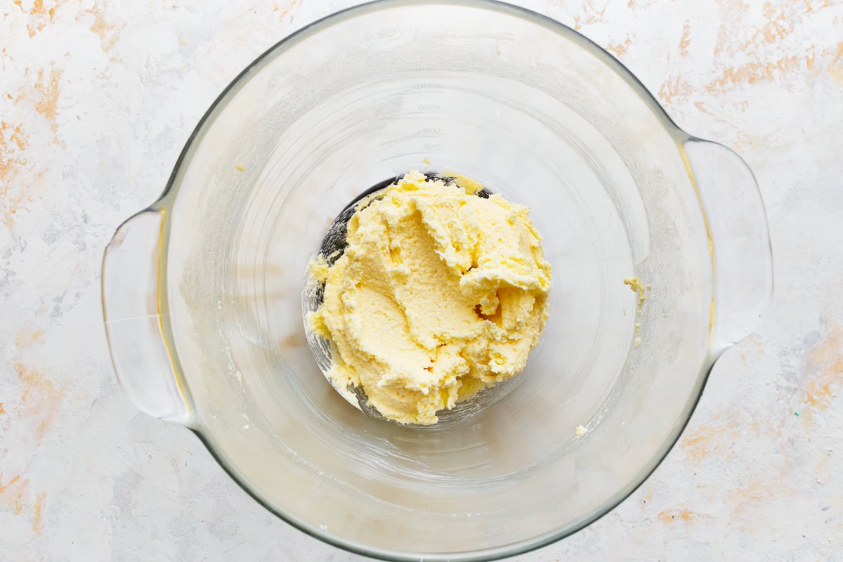 Butter and sugar creamed together in a glass mixing bowl.