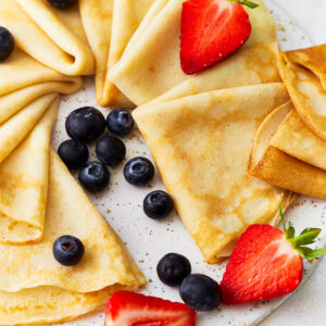 triangles of gluten-free crepes arranged on a platter with fresh fruit.