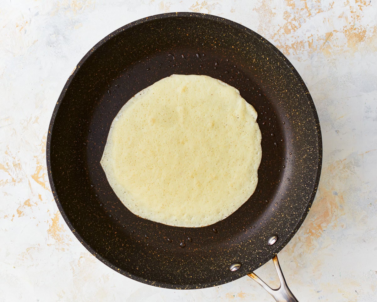cooking a gluten free crepe in a pan.