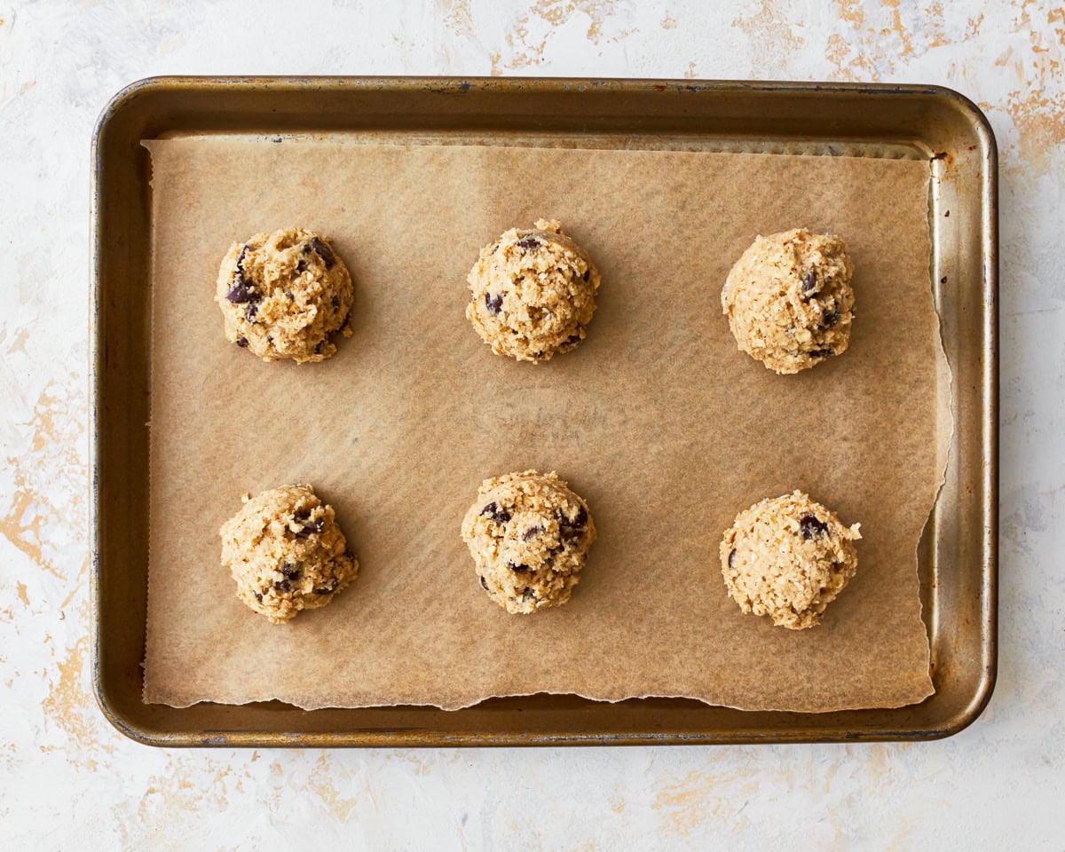 6 gluten-free oatmeal cookie dough balls on a baking sheet.