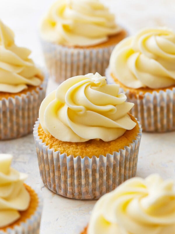 frosted gluten-free vanilla cupcakes in cupcake liners.