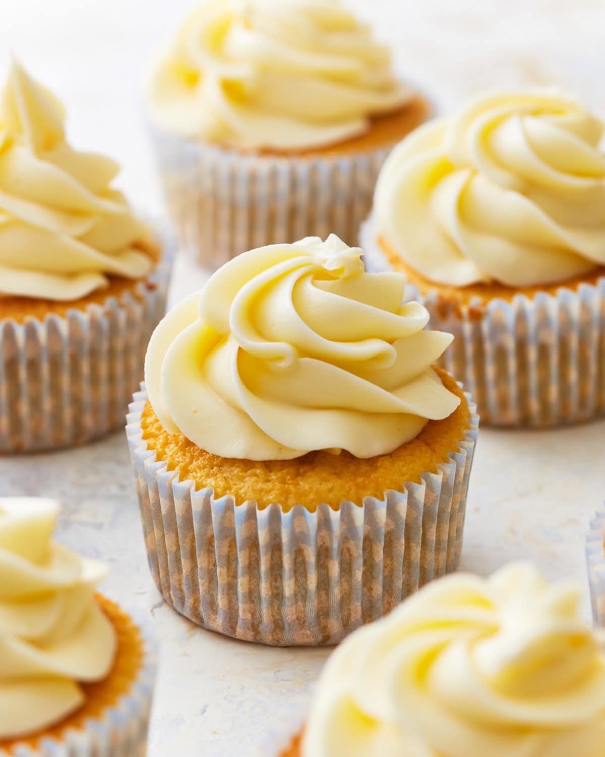frosted gluten-free vanilla cupcakes in cupcake liners.