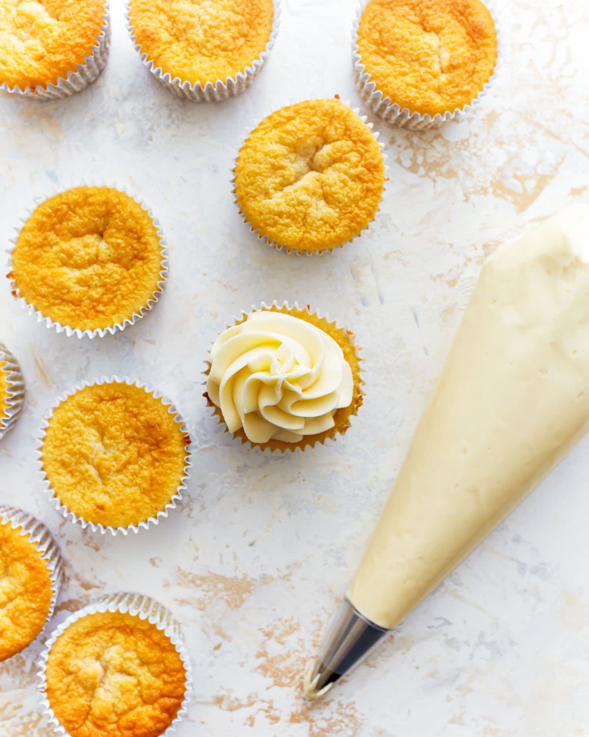 piping frosting on gluten-free vanilla cupcakes.