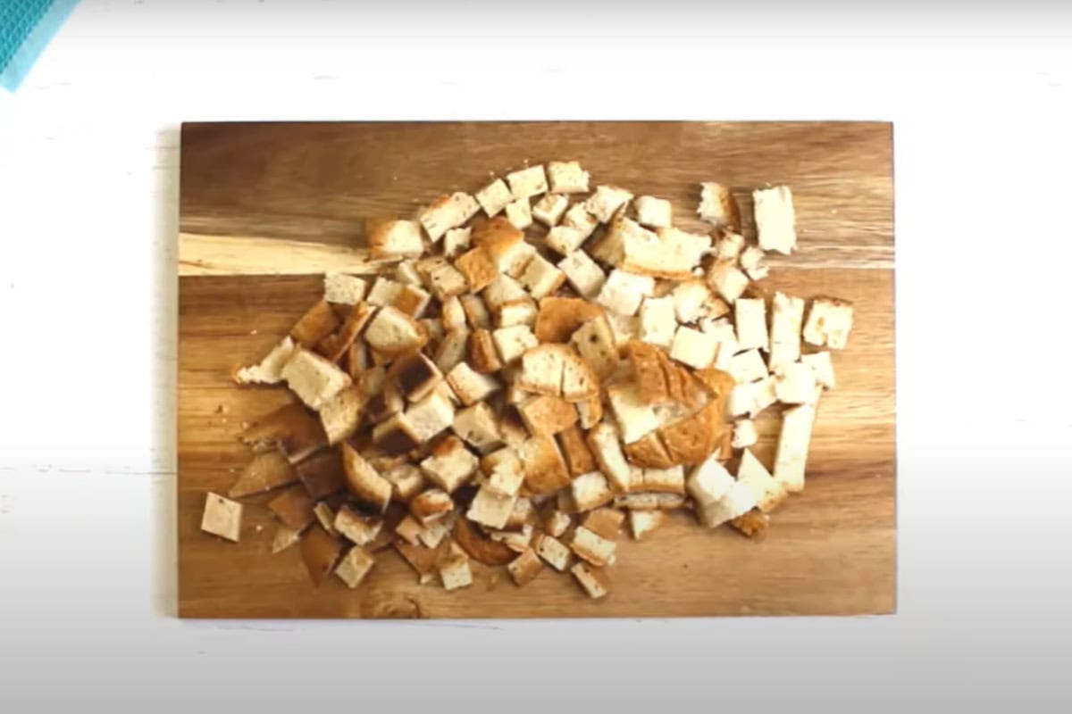 Gluten-free bread cut into cubes on a wooden chopping board.