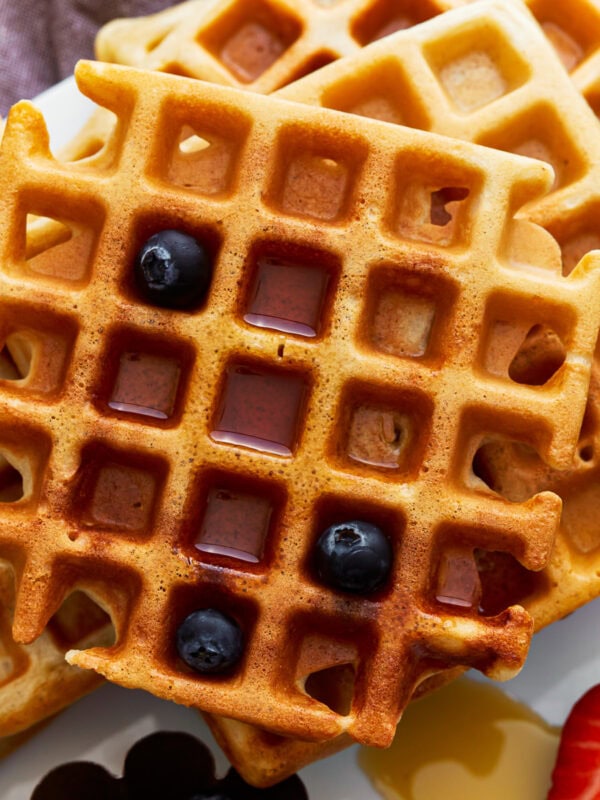 overhead view of a stack of gluten-free waffles with syrup and blueberries.
