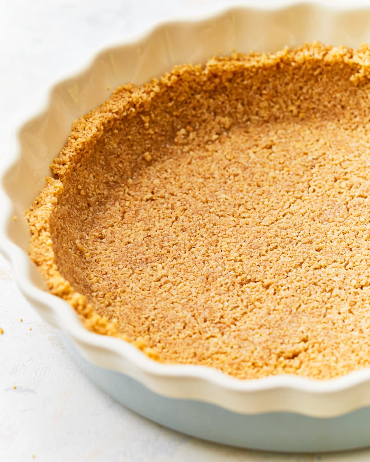 Side view close up of a gluten-free graham cracker crust in a pie dish.