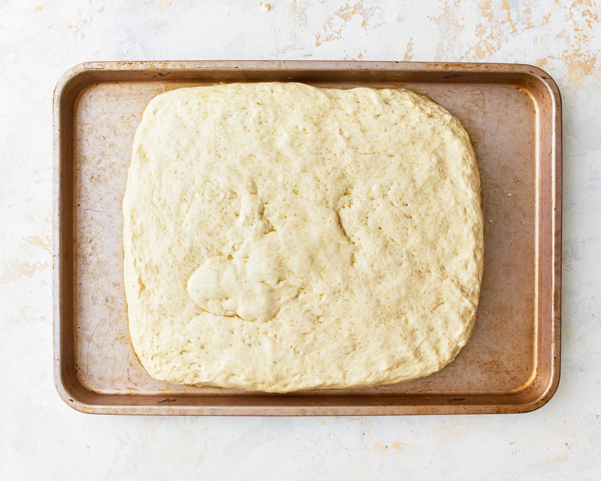 gluten-free focaccia dough in a rectangle on a baking sheet.