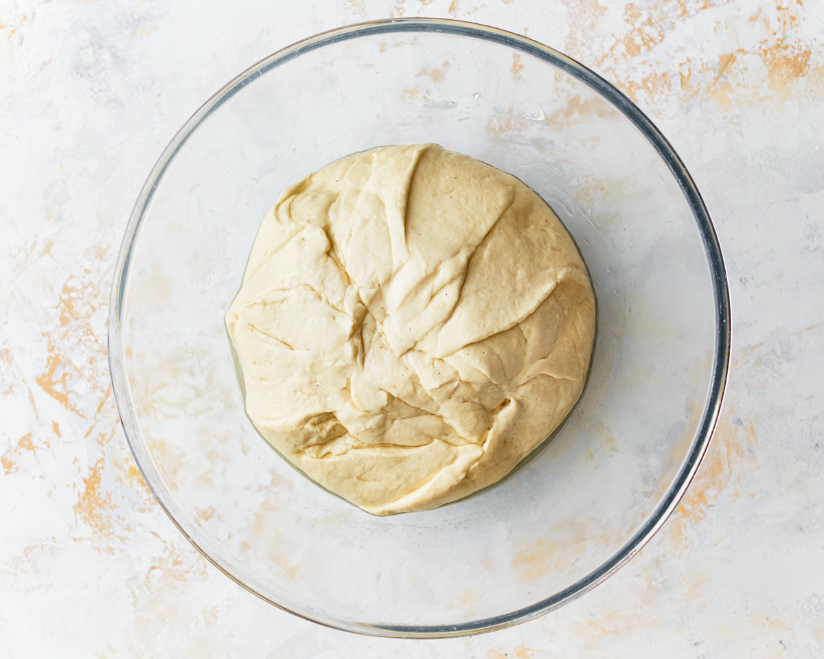 stiff gluten-free focaccia dough in a glass bowl.