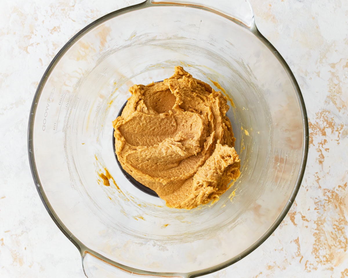 Butter and sugar mixture combined with egg and molasses in for gluten-free chocolate chip cookies in a glass mixing bowl