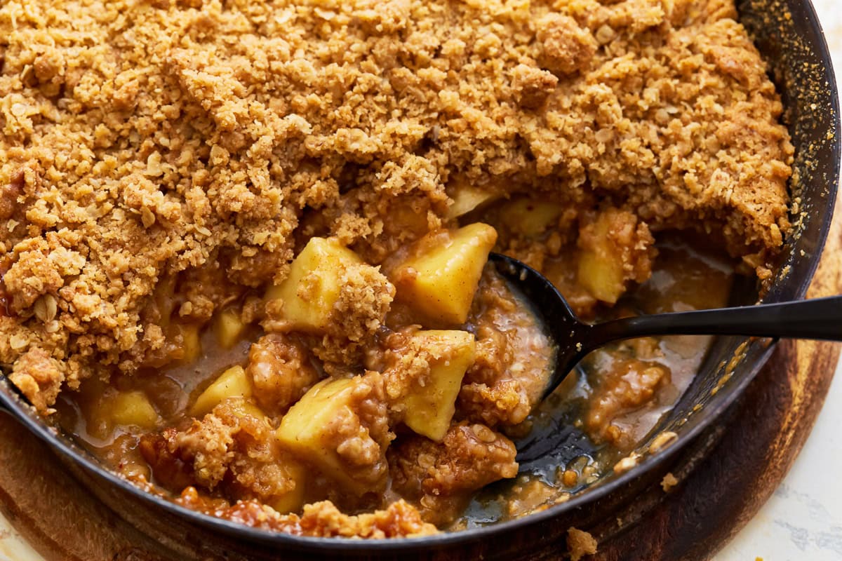 A spoon scooping some gluten-free apple crisp from a baking dish