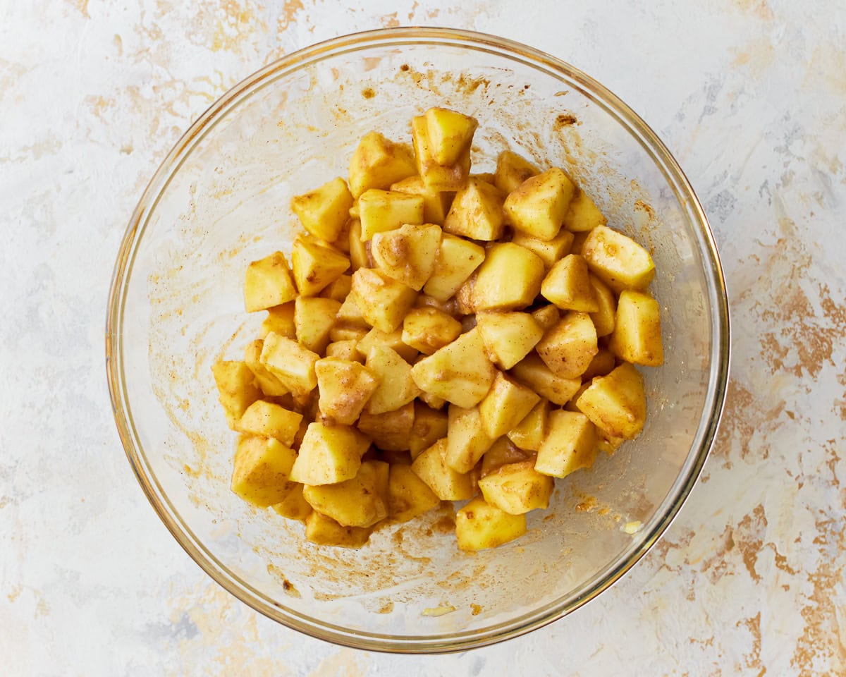 Chopped apples in a glass mixing bowl for gluten-free apple crisp