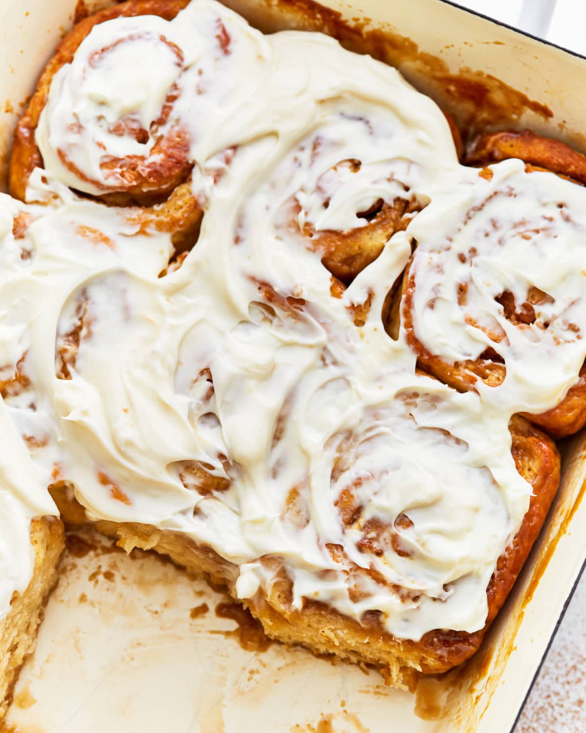 a tray of frosted gluten-free cinnamon rolls missing 2 rolls.