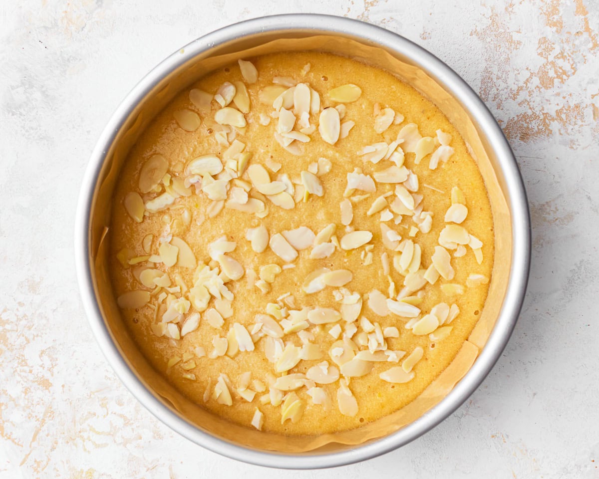 Almond flour cake batter poured into a baking tin and topped with sliced almonds.