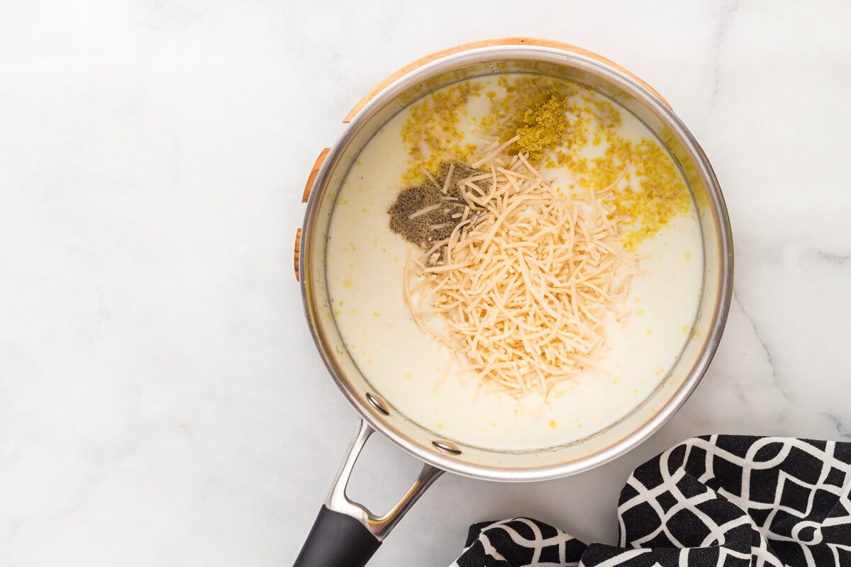 adding cheese, milk, and seasonings to a pan.