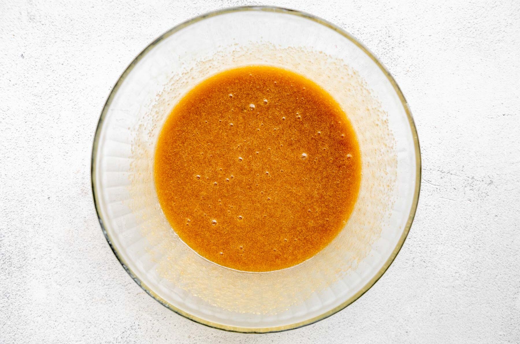 Wet ingredients for almond flour brownies in a glass mixing bowl.