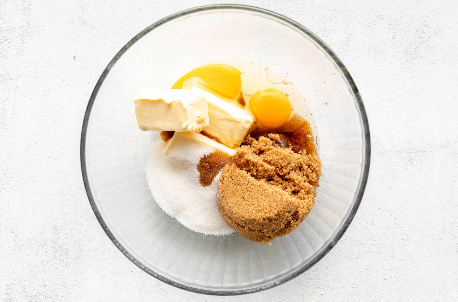 butter, white sugar, brown sugar, and egg in a glass bowl.
