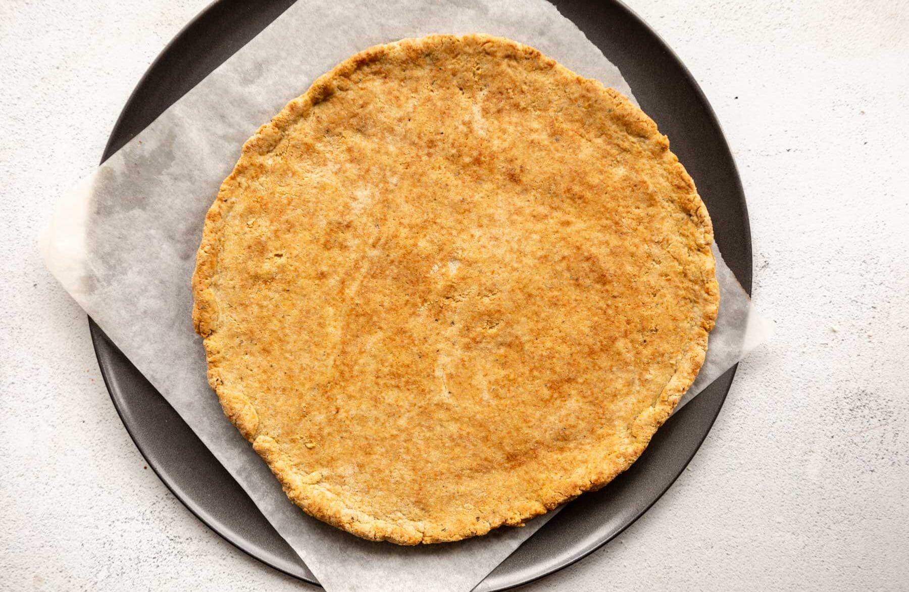 baked almond flour pizza crust on a parchment lined pizza pan.