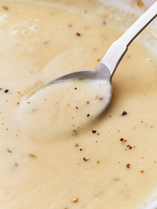 Side view of a spoon in a pan of gluten-free gravy.