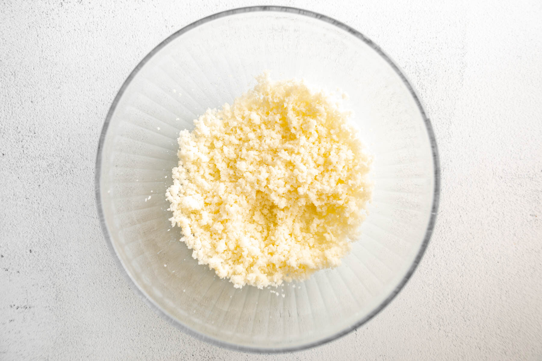 Butter and sugar in a glass mixing bowl.