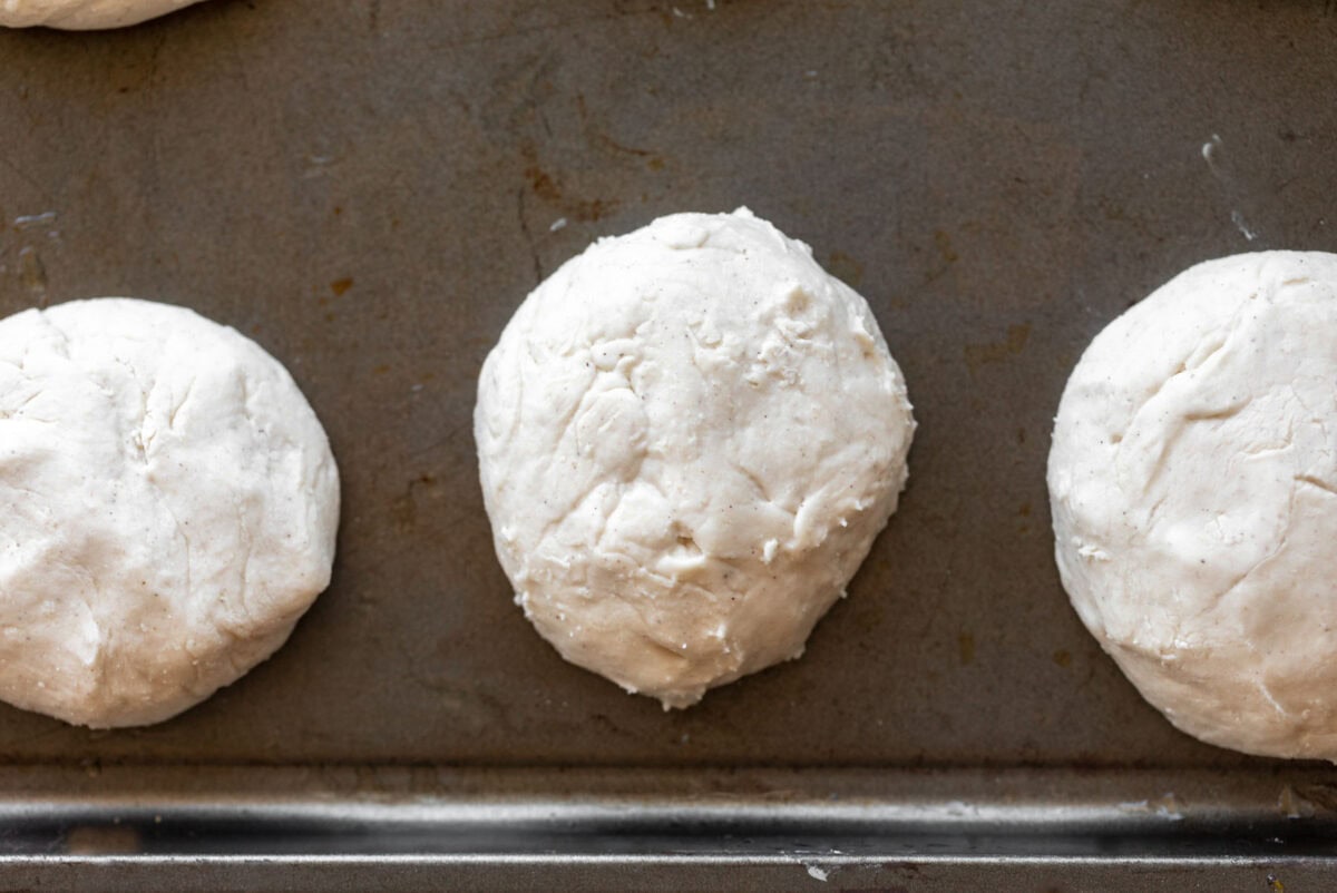 gluten-free english muffin dough balls on a baking sheet.