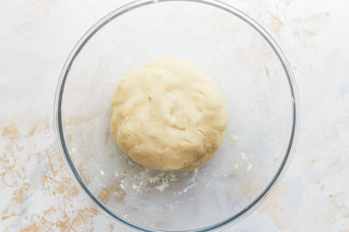 smooth gluten free gnocchi dough ball in a glass bowl.