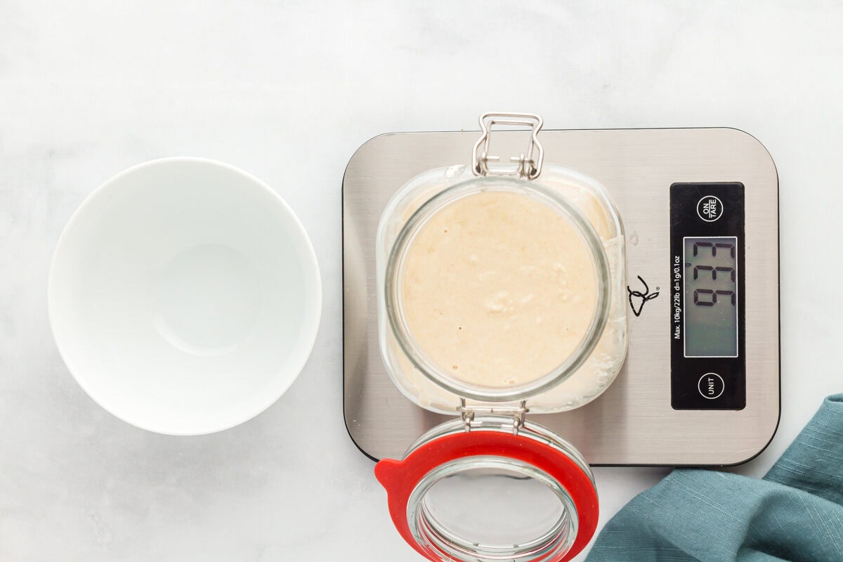 overhead view of gluten free sourdough starter in a glass jar on a scale.
