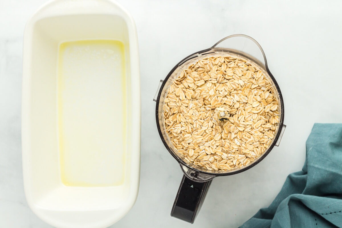 Old-fashioned oats in a food processor next to a greased baking dish.