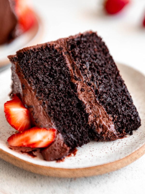 a slice of almond flour chocolate cake on a white plate with strawberries.