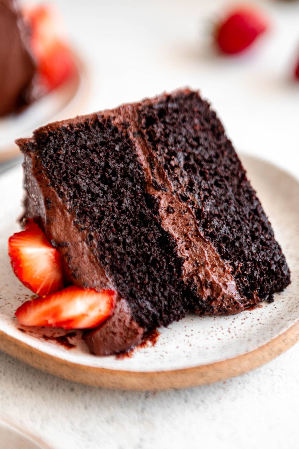 a slice of almond flour chocolate cake on a white plate with strawberries.