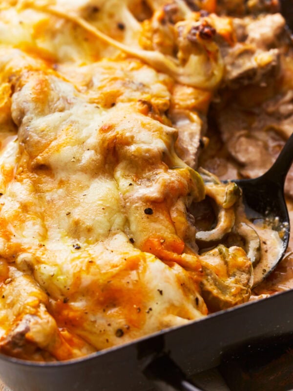 close up of a spoon scooping philly cheesesteak casserole from a casserole dish.