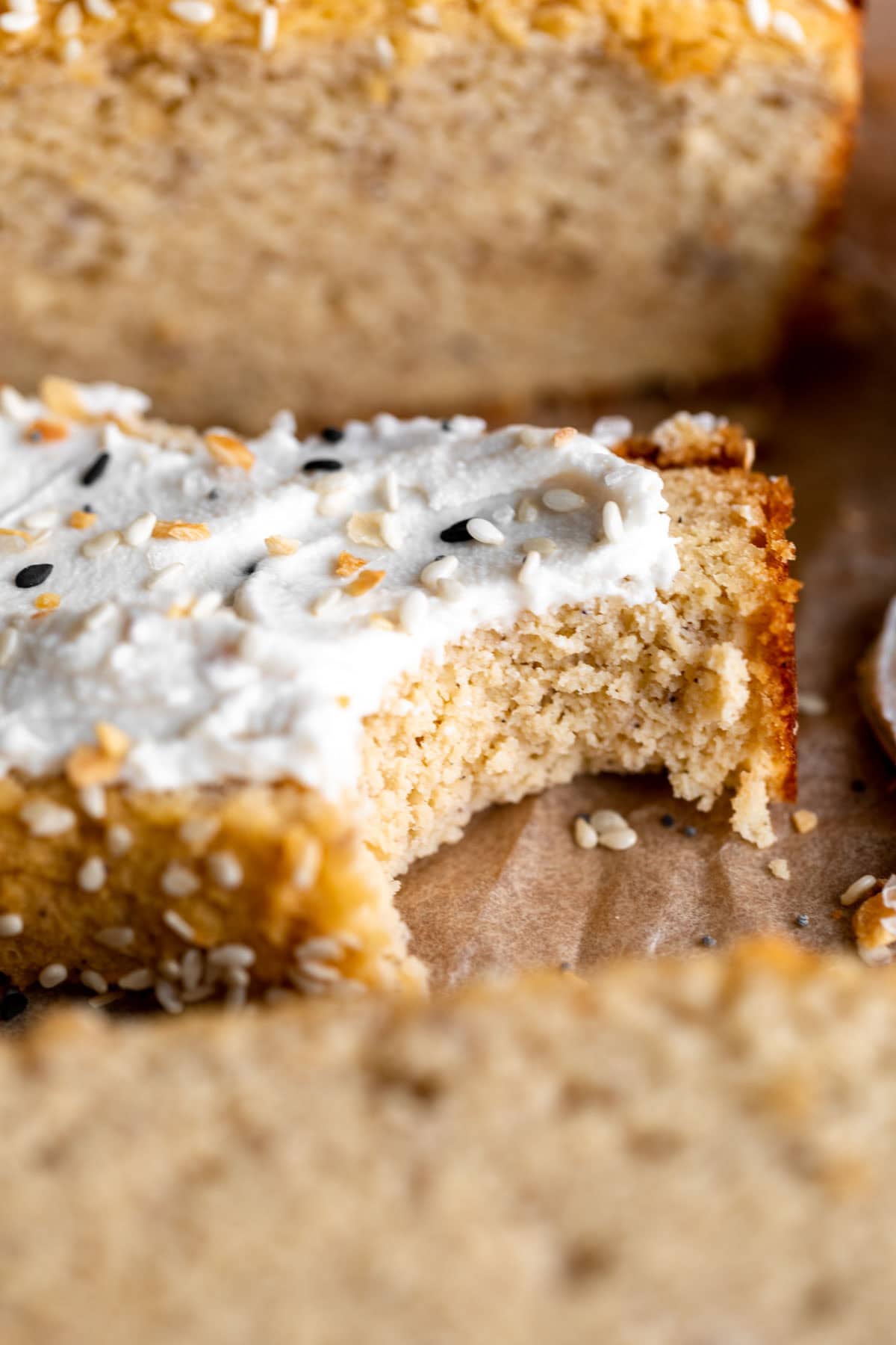 a bitten slice of coconut flour bread topped with cream cheese and everything bagel seasoning.