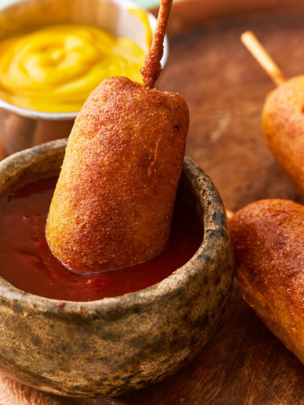 a gluten-free corn dog dipped in ketchup.