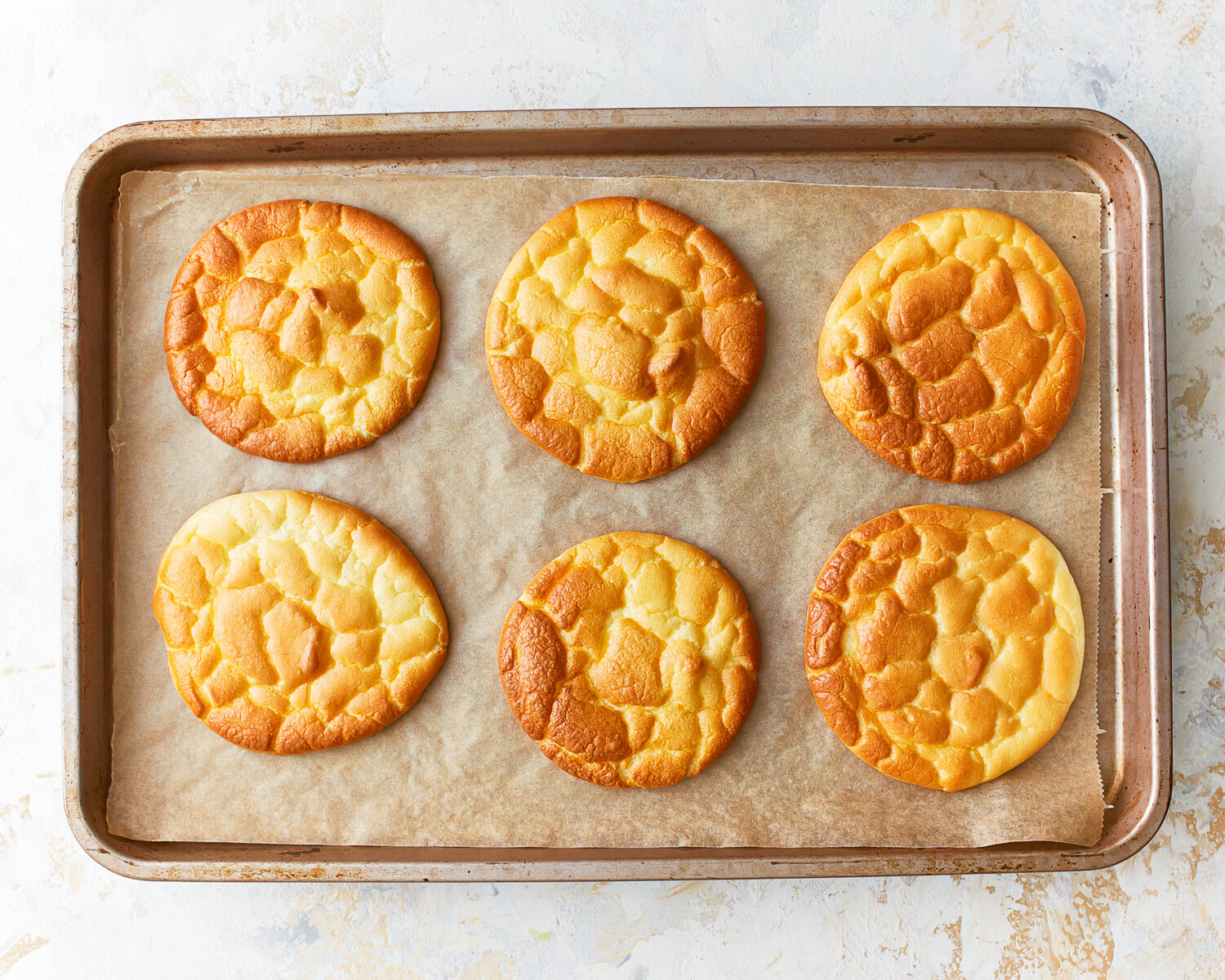 Six slices of freshly baked cloud bread on a parchment lined baking sheet.