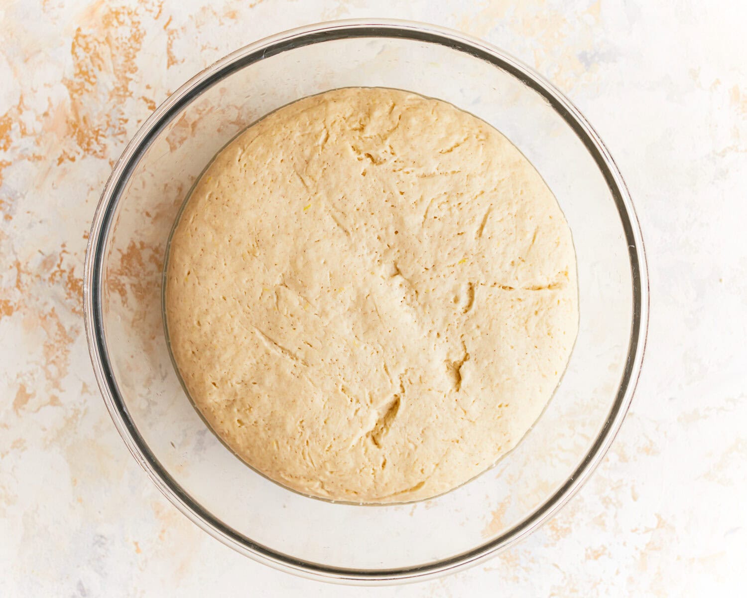 Risen dough for gluten free potato bread in a glass mixing bowl.