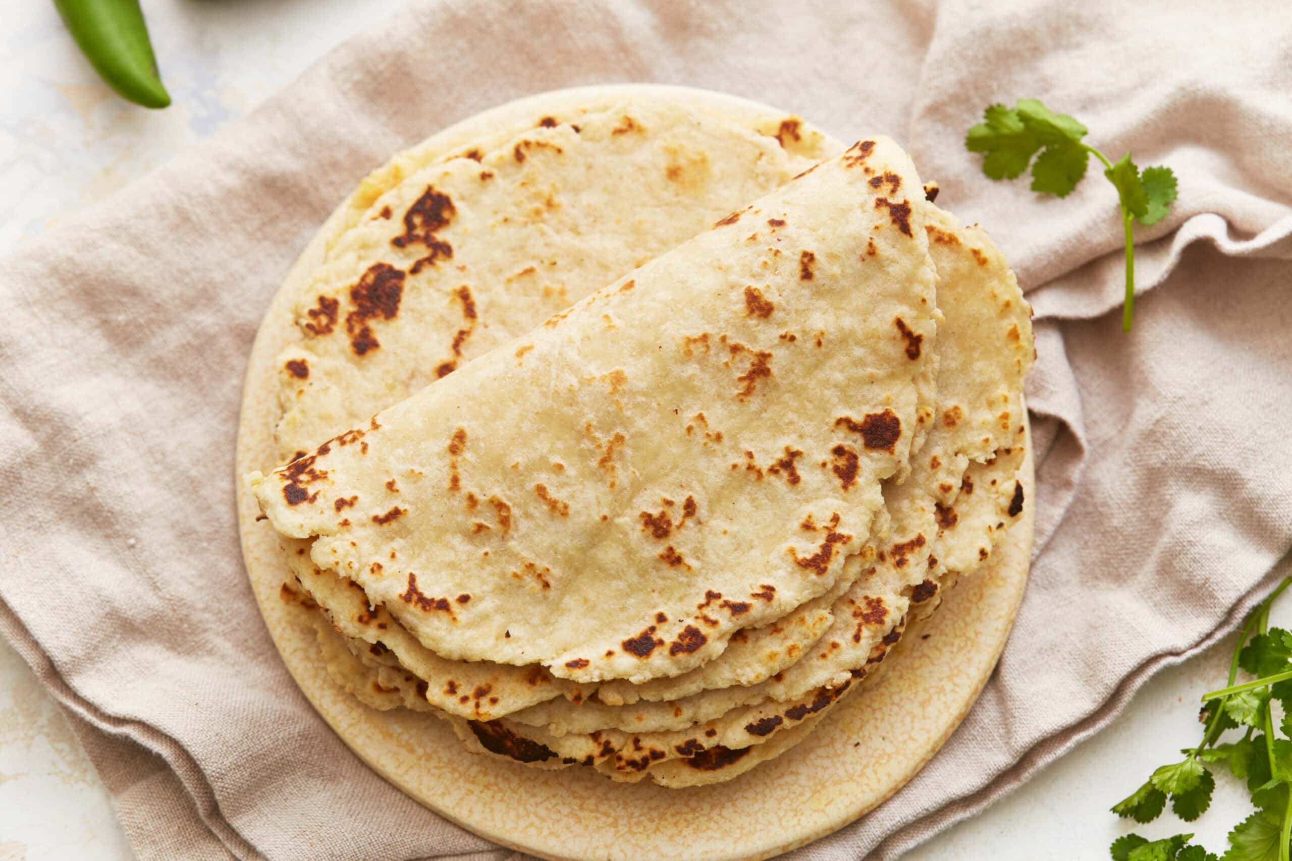 Overhead view of a stack of almond flour tortillas on a plate.