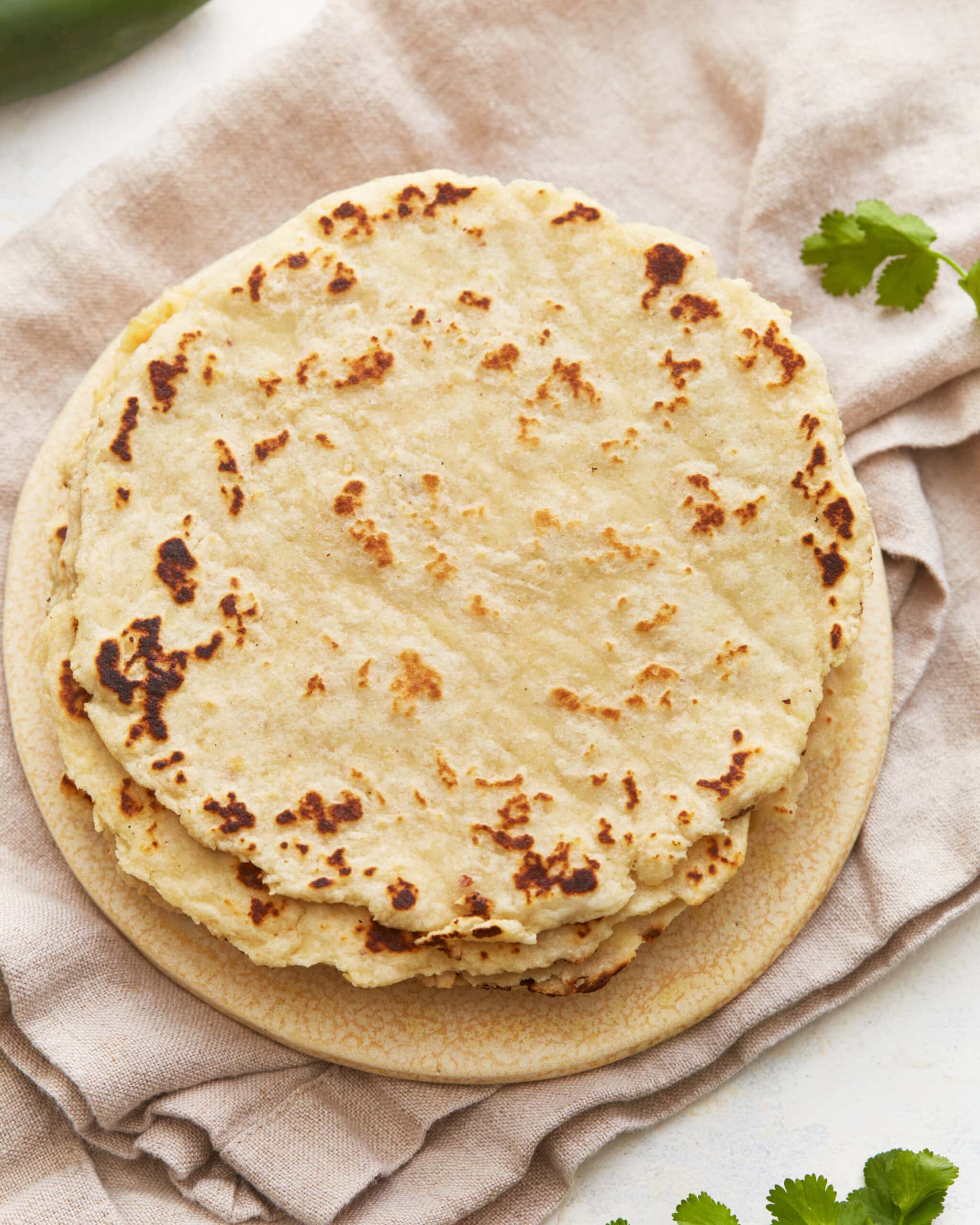 Overhead view of a stack of almond flour tortillas on a plate.