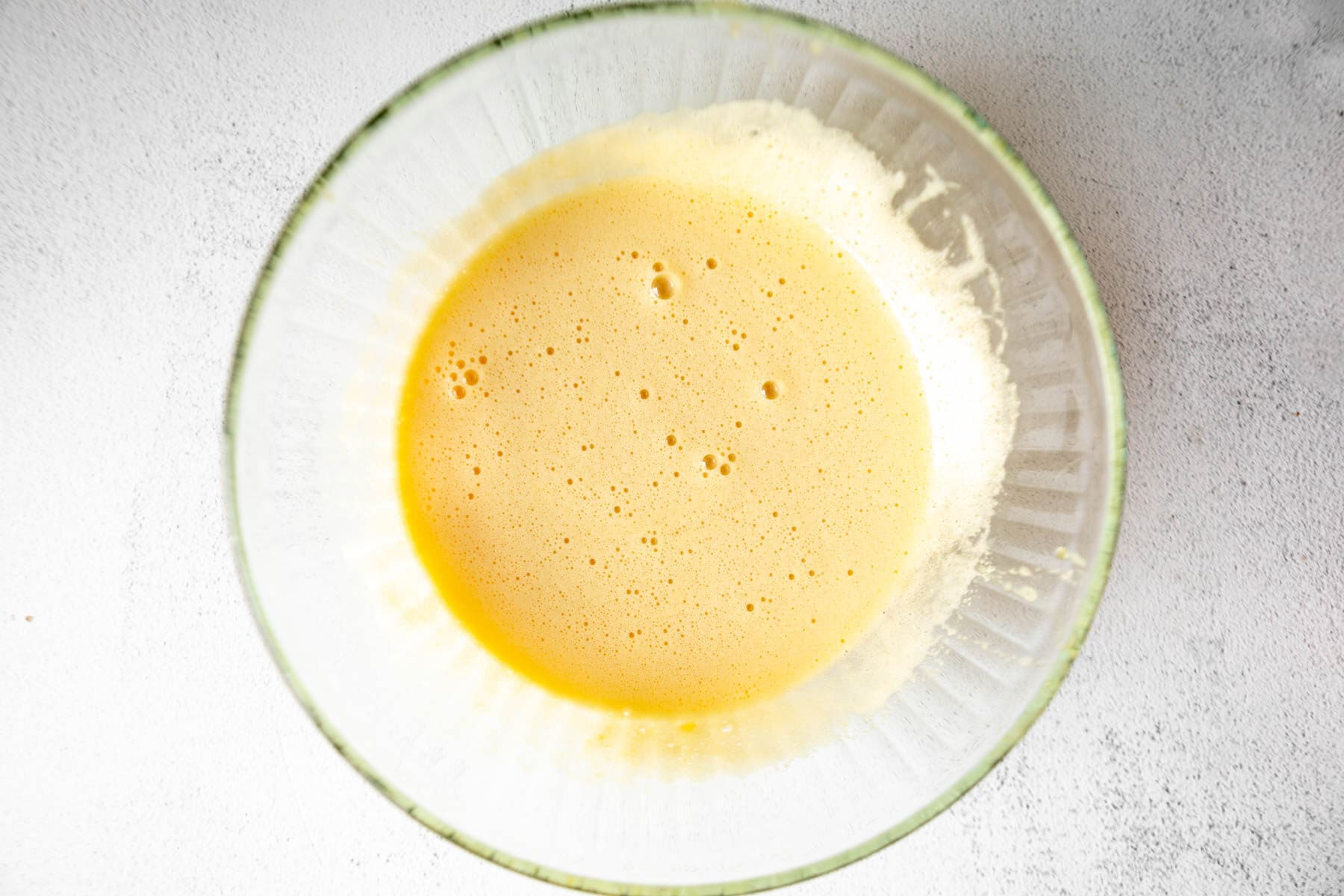 Wet ingredients for coconut flour brownies in a glass mixing bowl.