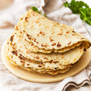 A stack of almond flour tortillas on a plate.