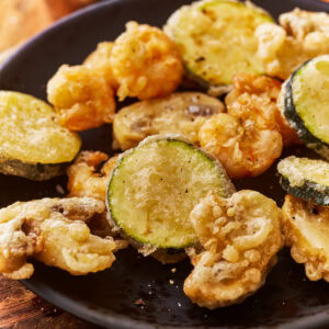 A plate of vegetables and shrimp cooked in a gluten free tempura batter.