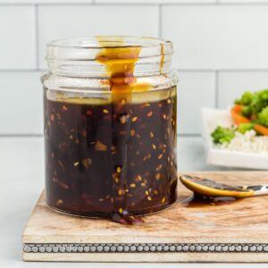 Side view of a glass jar filled with gluten free teriyaki sauce.