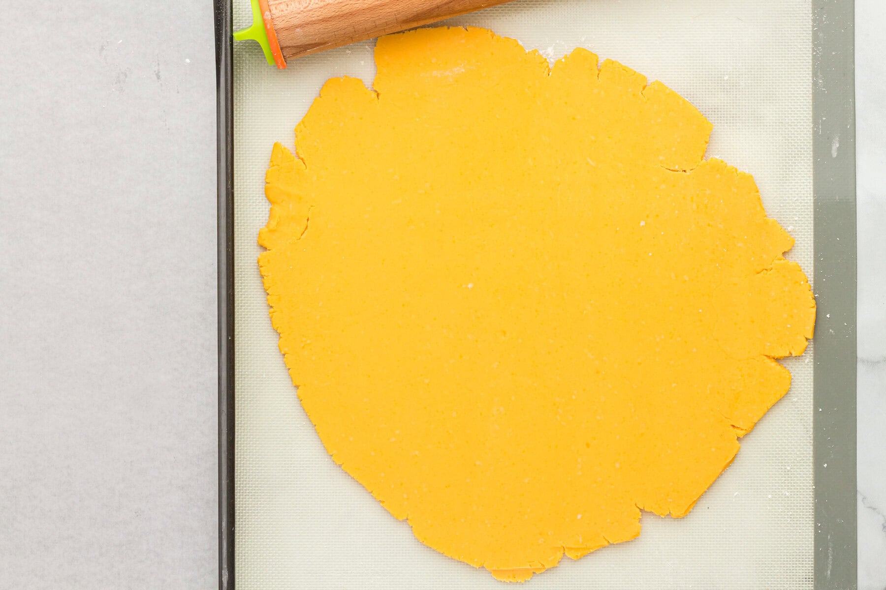 Rolled out gluten free cheez its dough on a silicone baking mat.