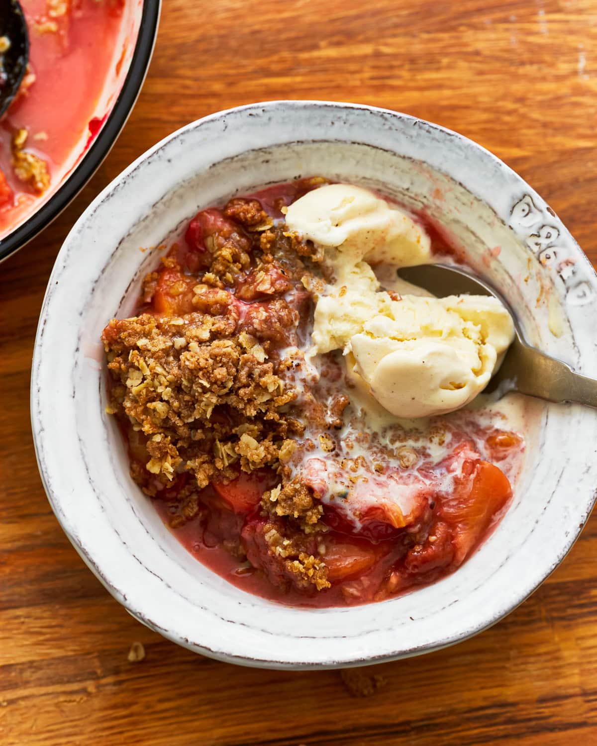 Gluten-free peach crisp in a bowl with vanilla ice cream.