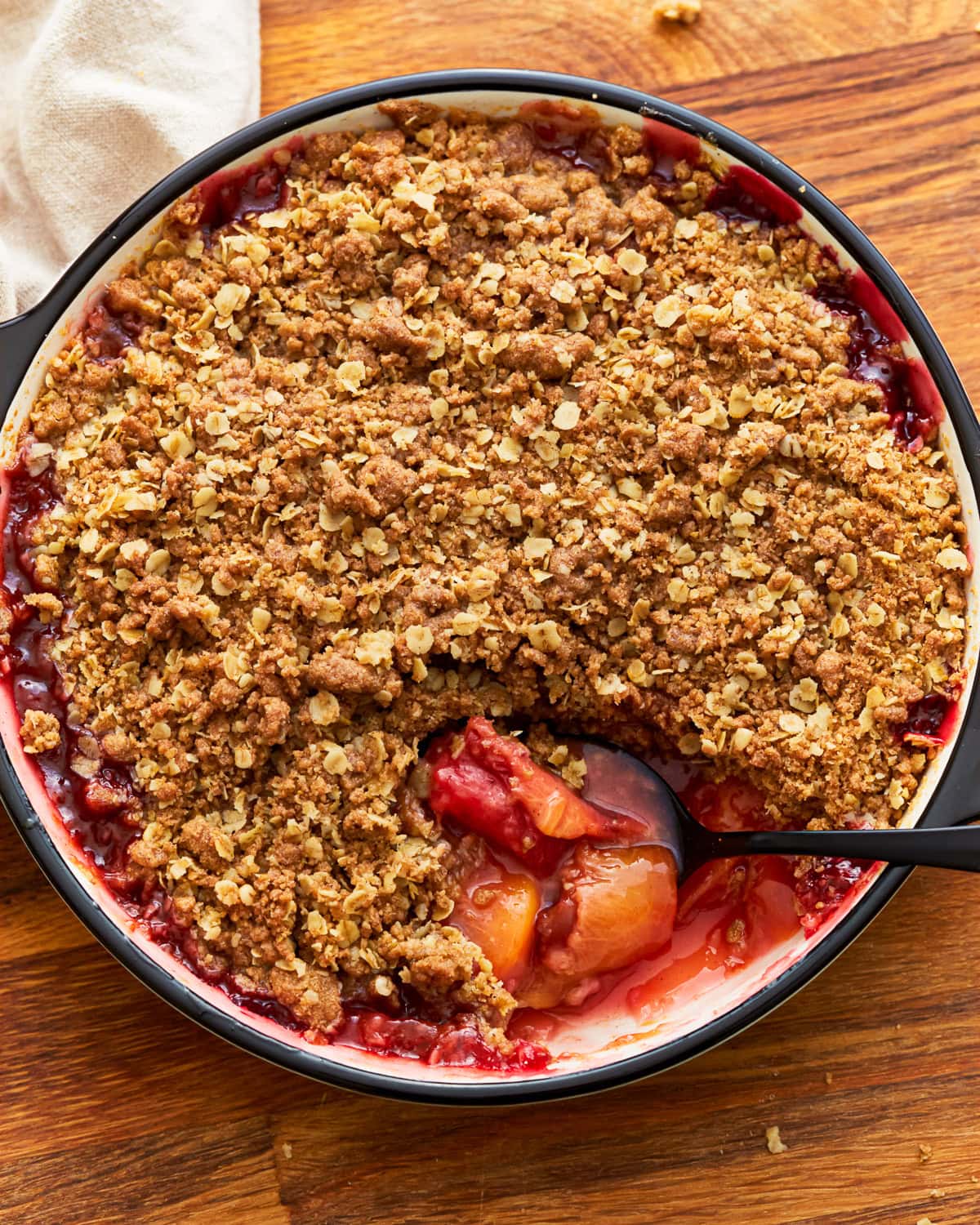 Gluten-free peach crisp in a baking dish with a spoon