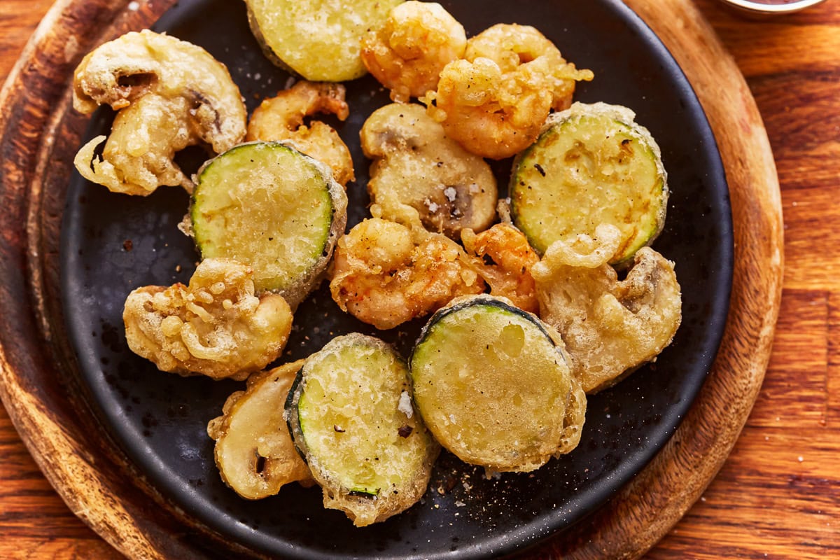 Overhead view of a plate of vegetables and shrimp cooked in a gluten free tempura batter.