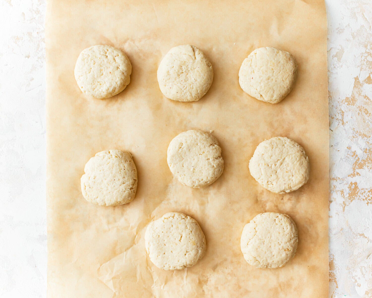 Almond flour tortillas dough portioned into eight balls on some patchment paper.